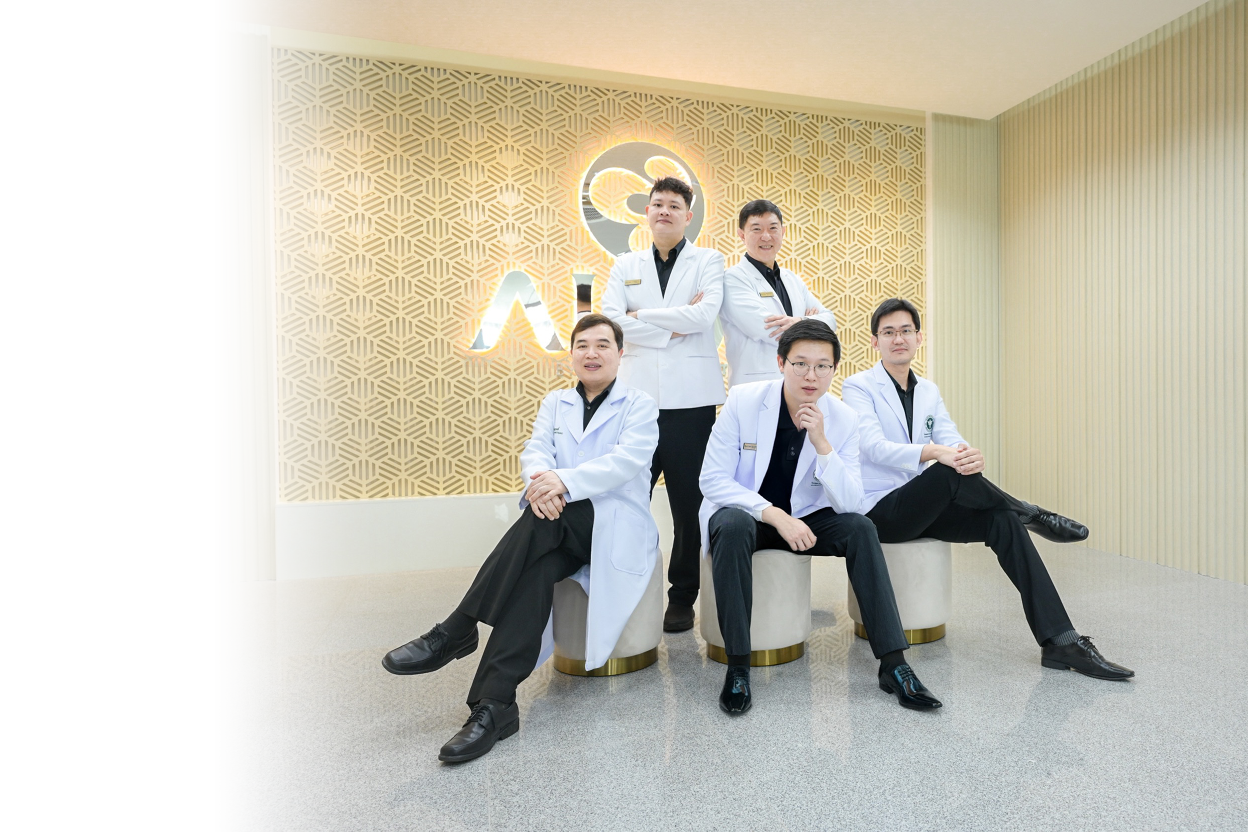ALIVE clinic medical team — group of doctors seated together in front of the ALIVE wall logo